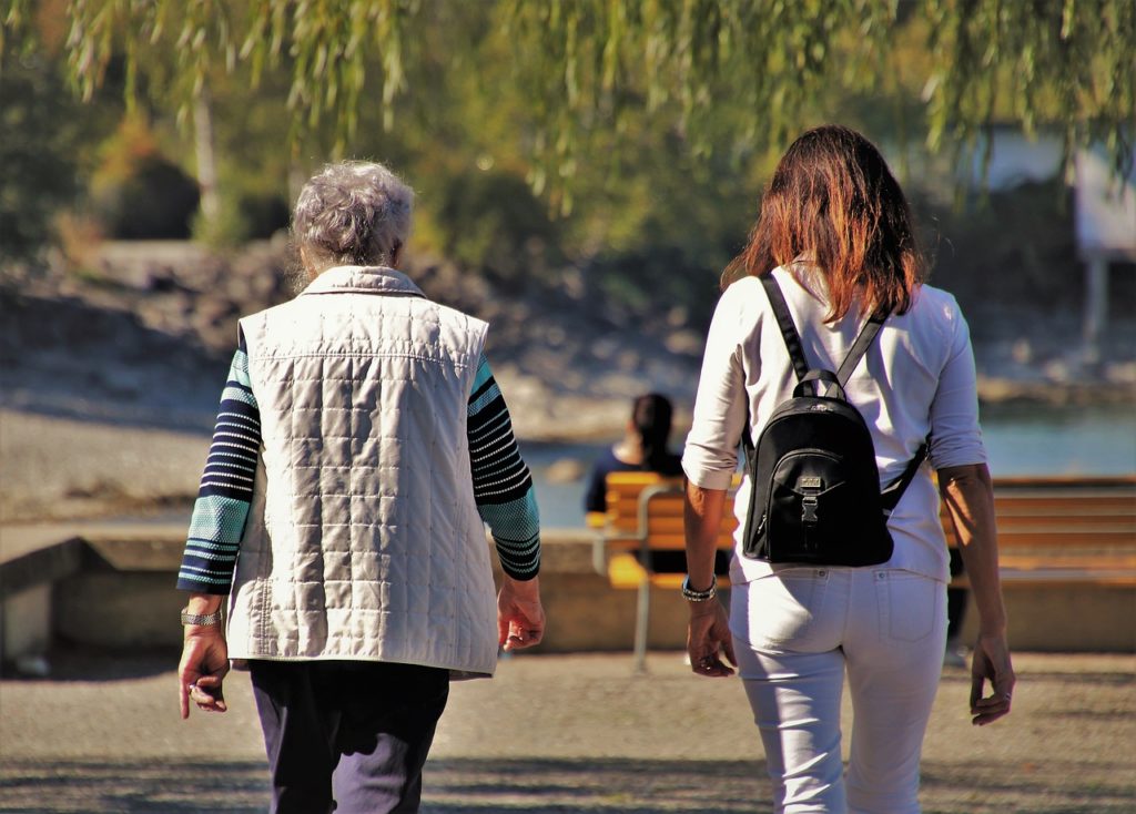 older woman and caregiver walking away; early Alzheimer's signs
